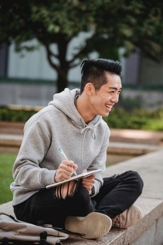 AAPI man smiling and writing in notepad