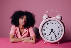 woman looking at big alarm clock